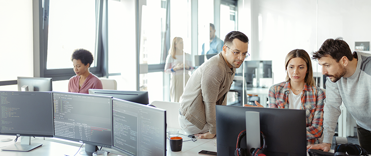 Three people in an office looking at a computer monitor.