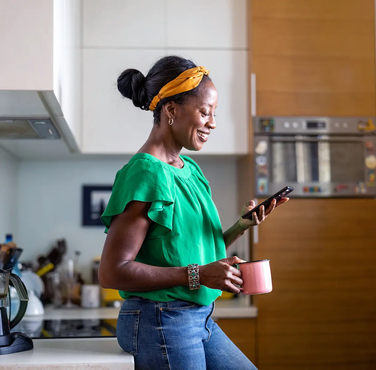 Smiling, mature woman using smartphone in kitchen at home