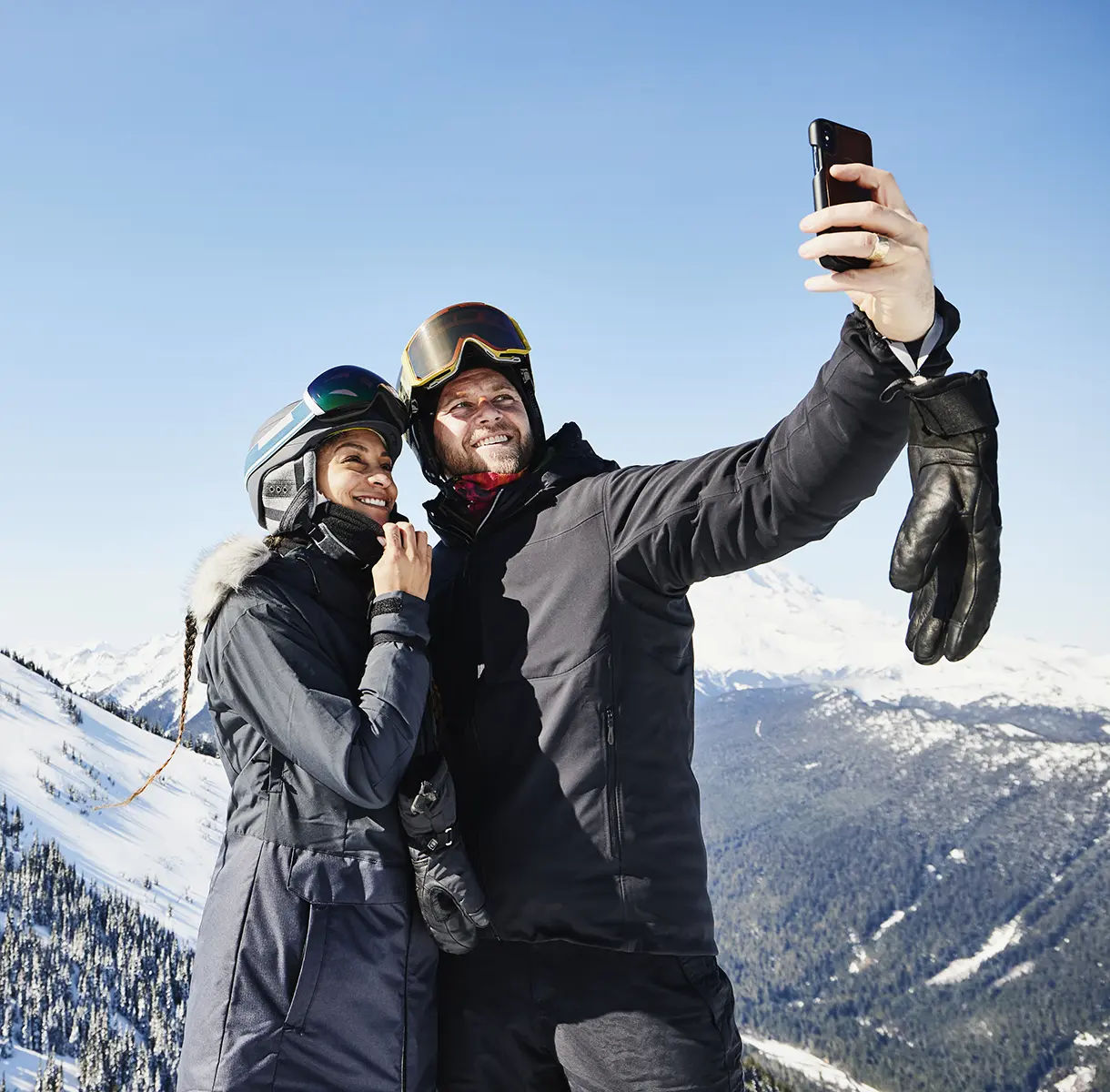 Couple in ski gear on mountain taking selife