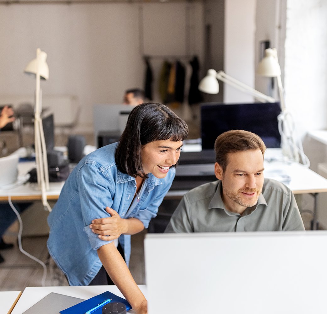 Man at computer with female co-worker looking over his shoulder